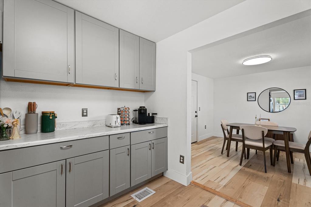 A kitchen area with gray cabinets and white countertops opens into a dining room — 204 6TH AVENUE NW, RUSKIN, FL