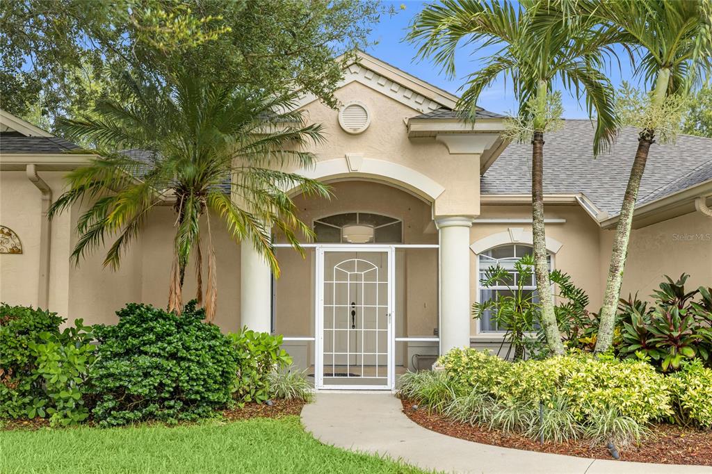 A living room with light wood floors, a white sofa, and a view of a pool — 6718 WILLOW POND LANE, SARASOTA, FL