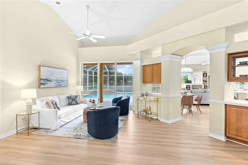 A living room with a wicker ottoman, two navy chairs, and a view of a pool — 6718 WILLOW POND LANE, SARASOTA, FL