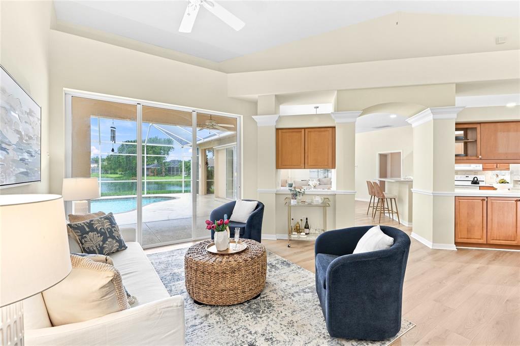 A living room with a white sofa, two blue armchairs, and a dining area beyond — 6718 WILLOW POND LANE, SARASOTA, FL