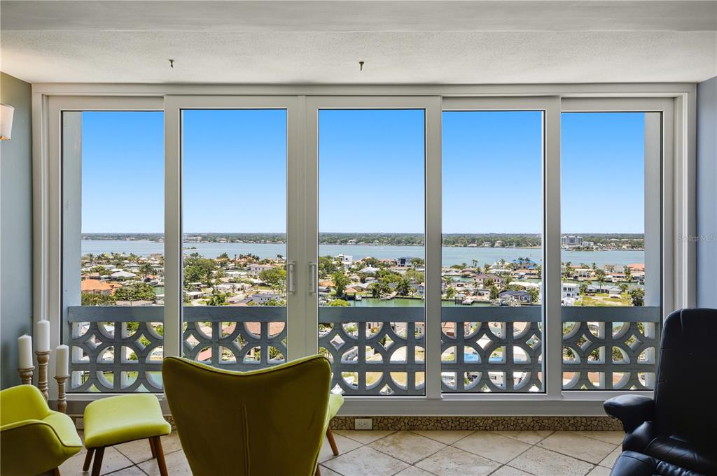 A living room features floor-to-ceiling sliding glass doors with a panoramic view of the water — 31 ISLAND WAY UNIT 1404, CLEARWATER, FL
