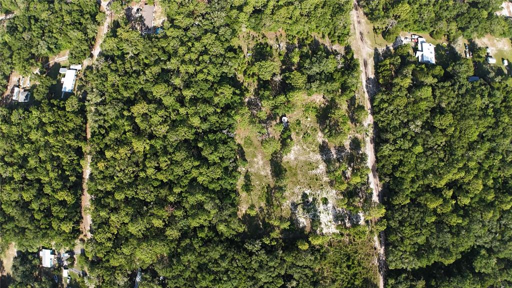 An aerial view shows a partially cleared, wooded lot bordered by a dirt road — SW 153RD LANE, DUNNELLON, FL
