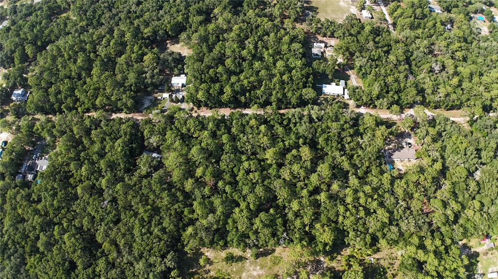 An aerial view shows a wooded lot surrounded by scattered houses and dirt roads — SW 153RD LANE, DUNNELLON, FL