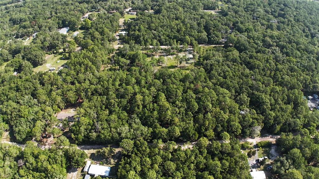 An aerial view shows a densely wooded lot with scattered houses and dirt roads — SW 153RD LANE, DUNNELLON, FL