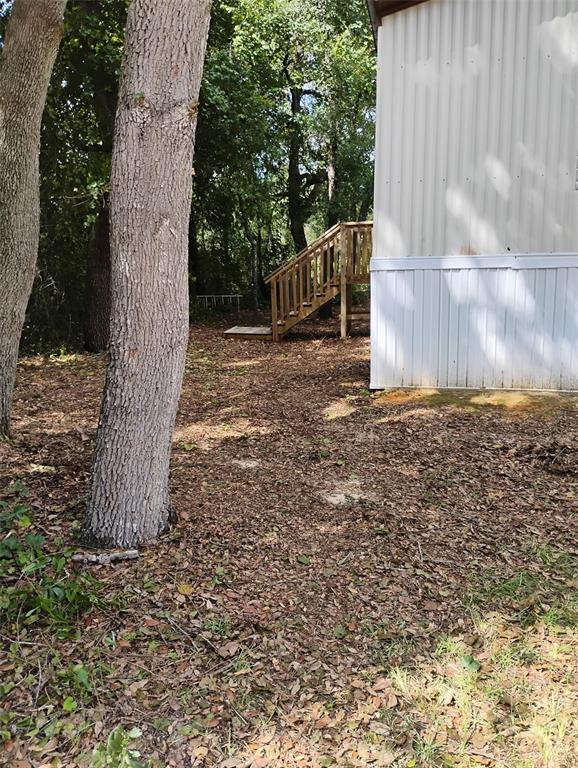 A wooden staircase leads to the side entrance of a mobile home near wooded trees — 6364 SWARTHMORE DRIVE, KEYSTONE HEIGHTS, FL
