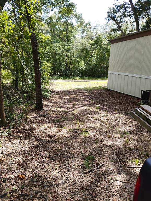 A view of a dirt path between a wooded area and the side of a building — 6364 SWARTHMORE DRIVE, KEYSTONE HEIGHTS, FL