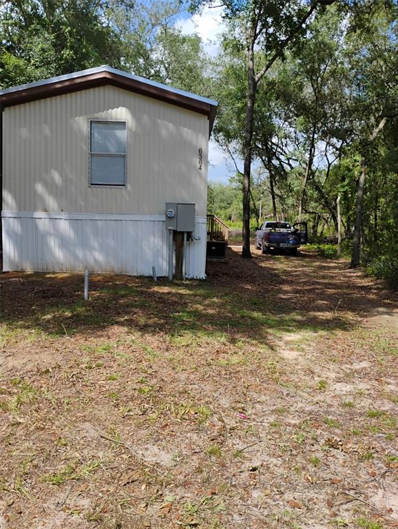 The exterior of a beige mobile home with a window and an electrical meter box — 6364 SWARTHMORE DRIVE, KEYSTONE HEIGHTS, FL
