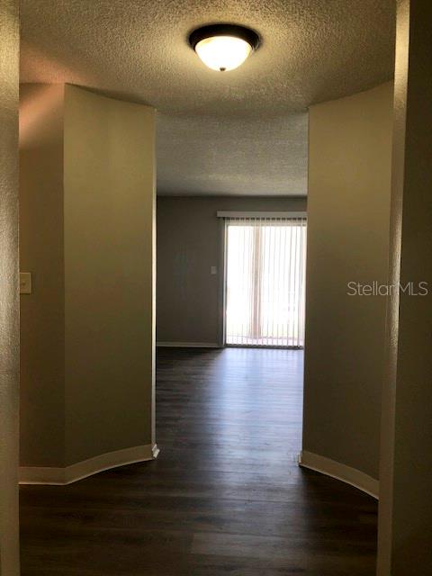 A hallway with wood-look flooring leads to a living area with a sliding glass door — 548 ORANGE UNIT 14, ALTAMONTE SPRINGS, FL