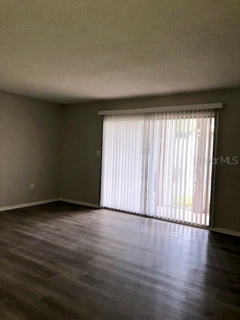 An empty room with gray walls, wood-look flooring, and vertical blinds covering a sliding door — 548 ORANGE UNIT 14, ALTAMONTE SPRINGS, FL
