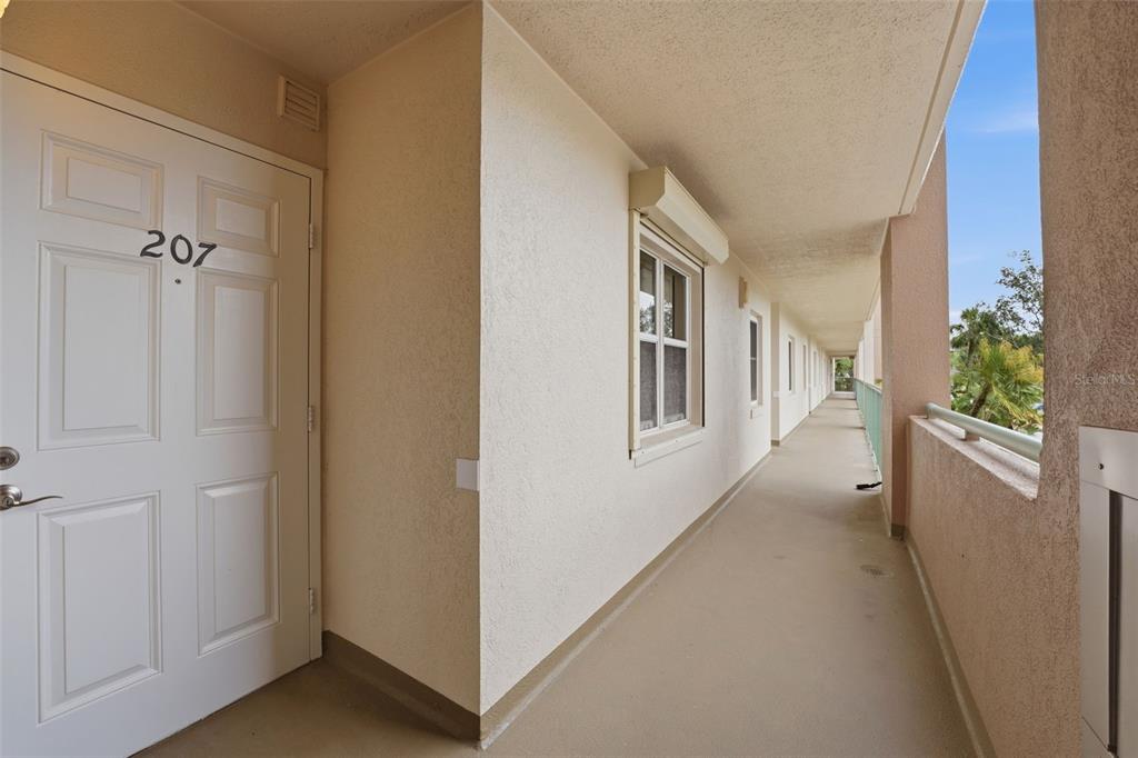 An outdoor apartment building walkway features a white door labeled 207 and a window — 2320 TERRA CEIA BAY BOULEVARD UNIT 207, PALMETTO, FL