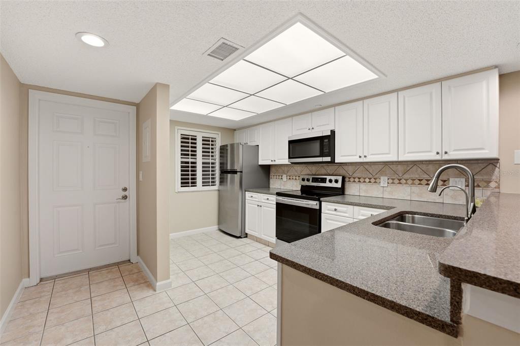 A kitchen featuring white cabinets, granite countertops, stainless steel appliances, and tile flooring — 2320 TERRA CEIA BAY BOULEVARD UNIT 207, PALMETTO, FL