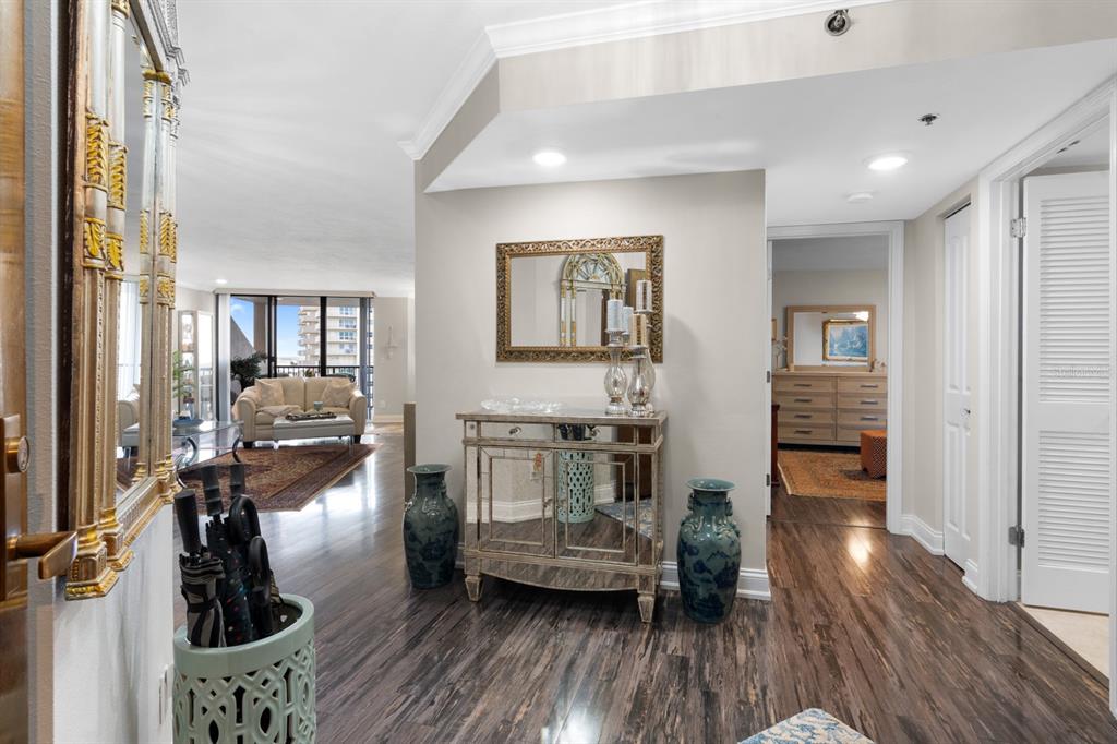 A foyer with dark wood flooring leads into a living area with a balcony view — 1600 GULF BOULEVARD UNIT 717, CLEARWATER BEACH, FL