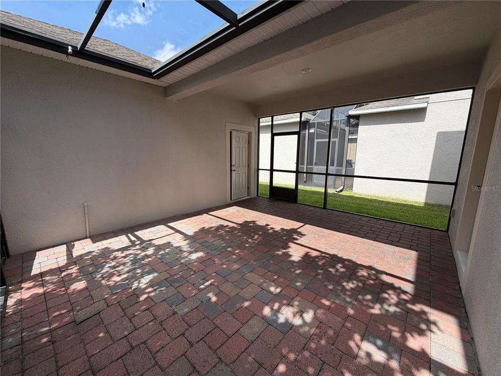 A covered patio features paver flooring, a screened enclosure, and a white exterior door — 15171 BRIDGEWATER CROSSINGS BOULEVARD, WINTER GARDEN, FL