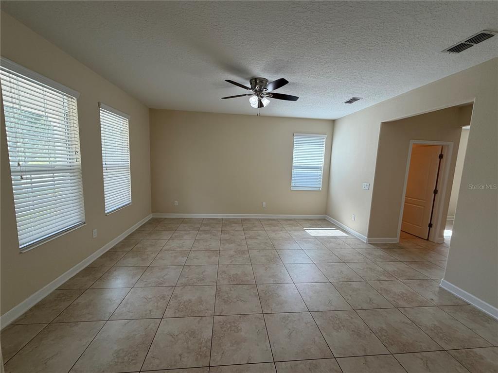 An empty room features beige walls, tile flooring, a ceiling fan, and three windows — 15171 BRIDGEWATER CROSSINGS BOULEVARD, WINTER GARDEN, FL