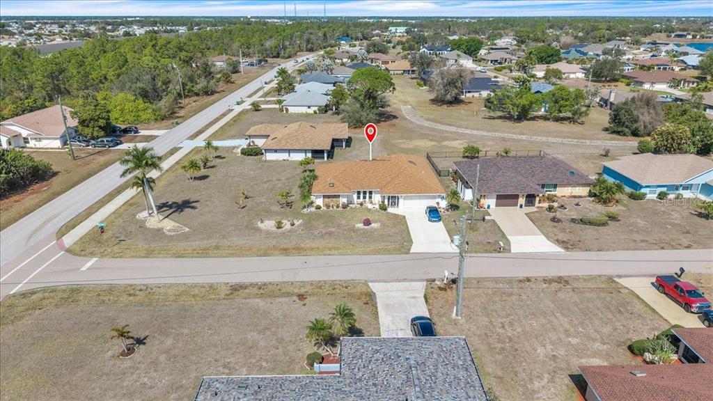 An aerial view shows a single-story house with a brown roof and a large yard — 1726 BLUE LAKE CIRCLE, PUNTA GORDA, FL