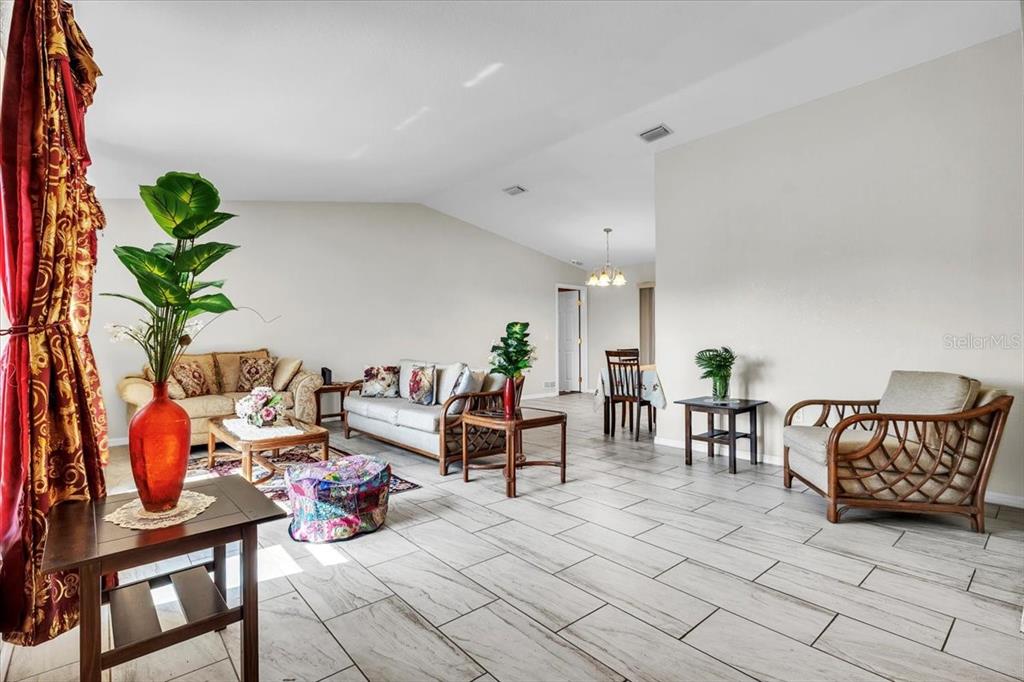 A bright living room features light tile flooring, neutral walls, and various seating arrangements — 1726 BLUE LAKE CIRCLE, PUNTA GORDA, FL