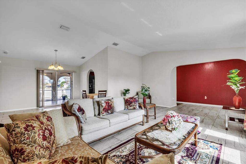 A living room features light tile floors, a vaulted ceiling, and a red accent wall — 1726 BLUE LAKE CIRCLE, PUNTA GORDA, FL