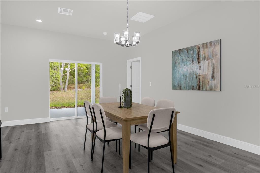 A dining room features a wooden table, six chairs, a chandelier, and sliding glass doors — 1233 W SHADY LANE, DUNNELLON, FL
