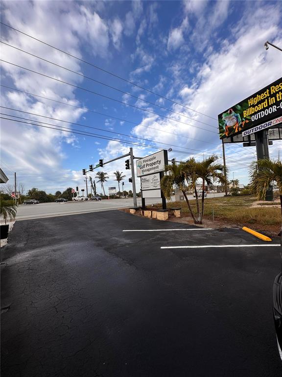 A paved parking lot sits in front of a commercial sign and a large billboard — 1221 S MCCALL ROAD UNIT B, ENGLEWOOD, FL