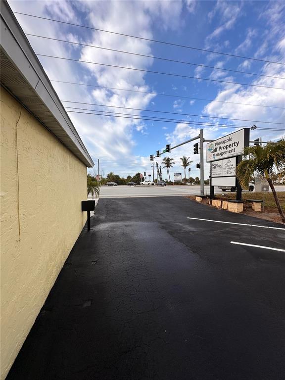 A paved parking lot sits beside a yellow building with a business sign nearby — 1221 S MCCALL ROAD UNIT B, ENGLEWOOD, FL