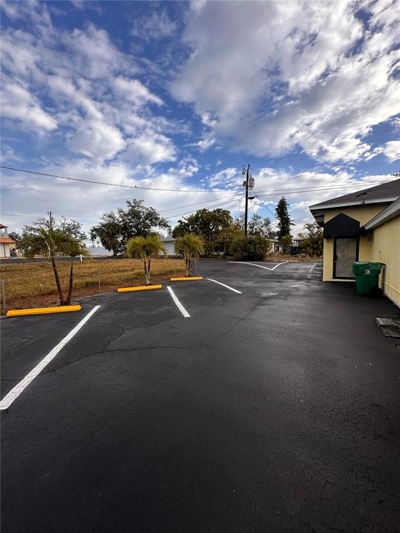 An asphalt parking lot with painted lines and yellow wheel stops sits beside a building — 1221 S MCCALL ROAD UNIT B, ENGLEWOOD, FL