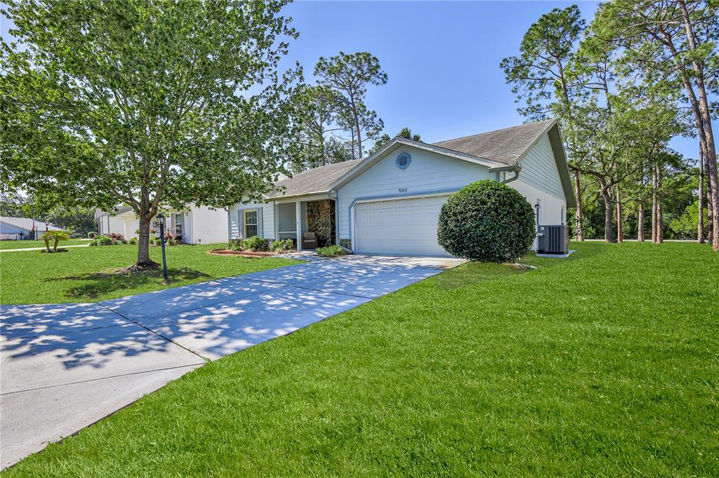 A single-story house with a light blue exterior, a two-car garage, and a concrete driveway — 7088 CROWN OAKS DRIVE, SPRING HILL, FL