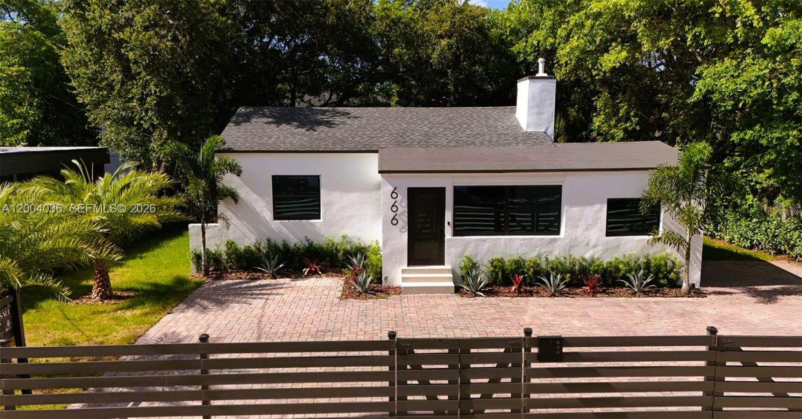 A white single-story house with a brick driveway and a horizontal slat fence — 666 NE 62nd St, Miami FL 33138, MIAMI, FL