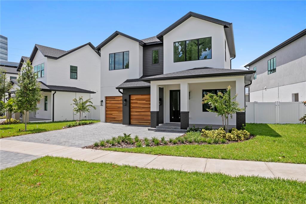 A two-story house with a paved driveway, wood-paneled garage doors, and a covered front porch — 3613 W NORTH A STREET, TAMPA, FL