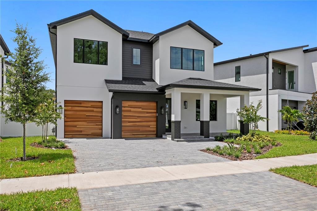 A two-story modern house with a white facade, dark trim, and two wood-paneled garage doors — 3613 W NORTH A STREET, TAMPA, FL