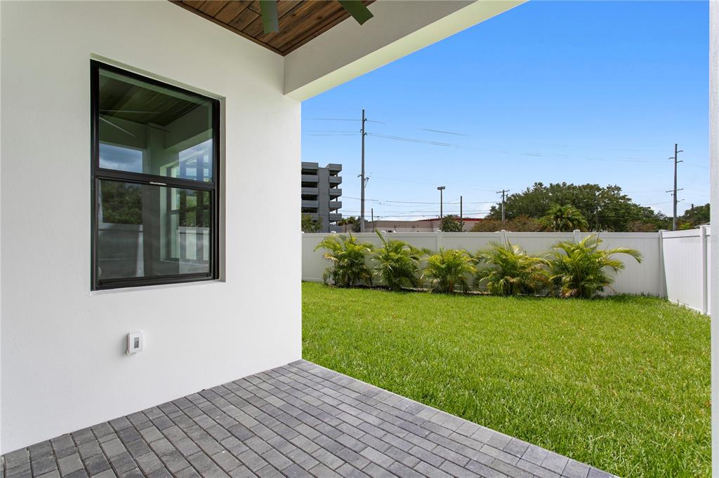 An open-concept living room and kitchen featuring light wood floors, a staircase, and sliding doors — 3613 W NORTH A STREET, TAMPA, FL
