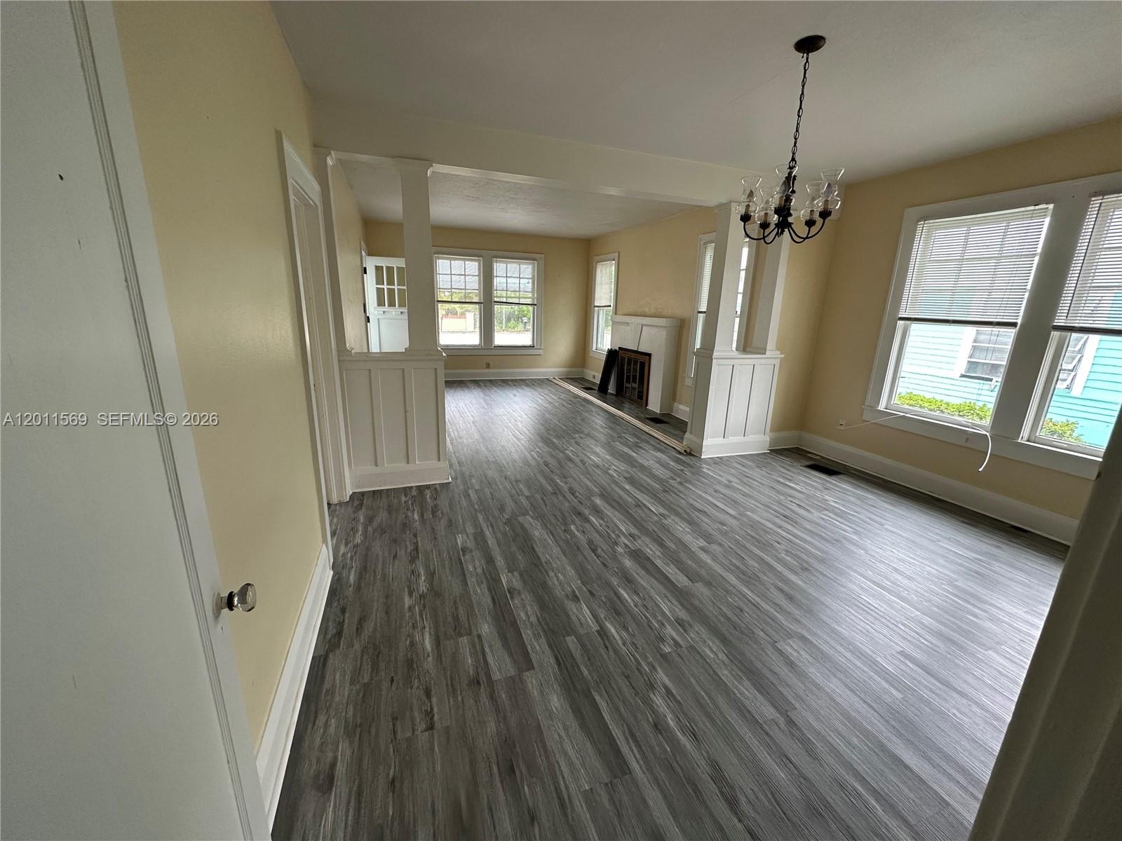 An open-concept living area features light yellow walls, gray wood-look flooring, and white columns — 1870 Lakeview Rd # 1, Sebring FL 33870, SEBRING, FL
