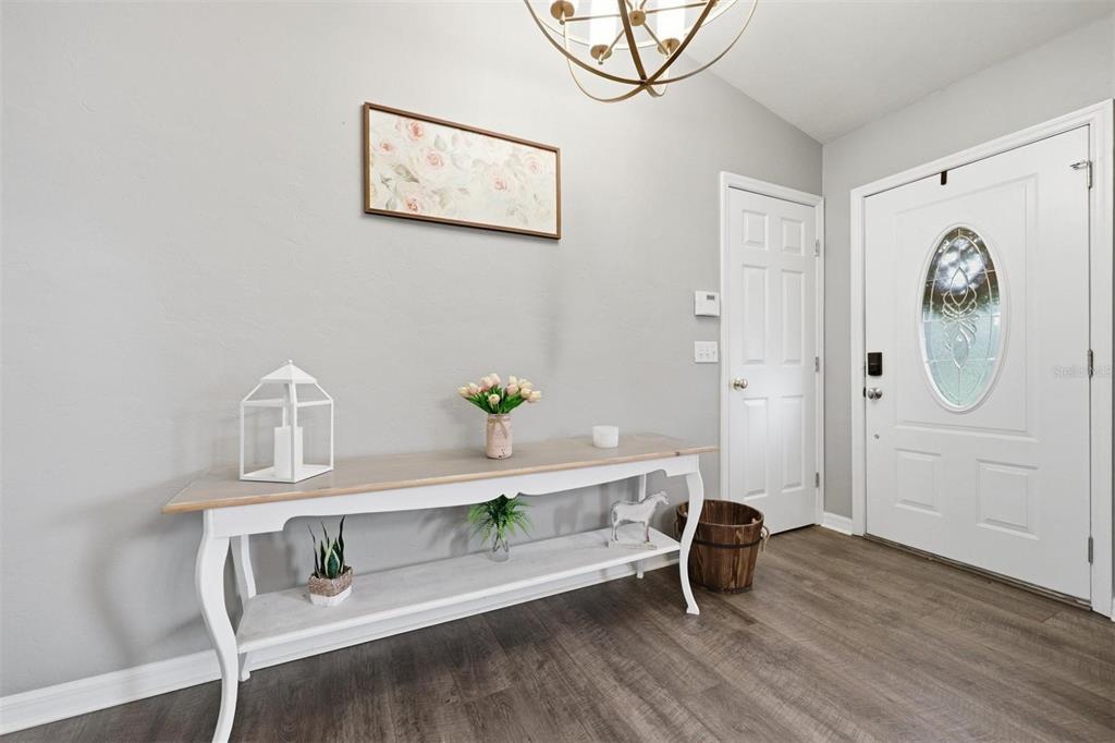 An entryway features a white console table, wood-look flooring, and a white front door — 3460 SE COUNTY ROAD 337, TRENTON, FL