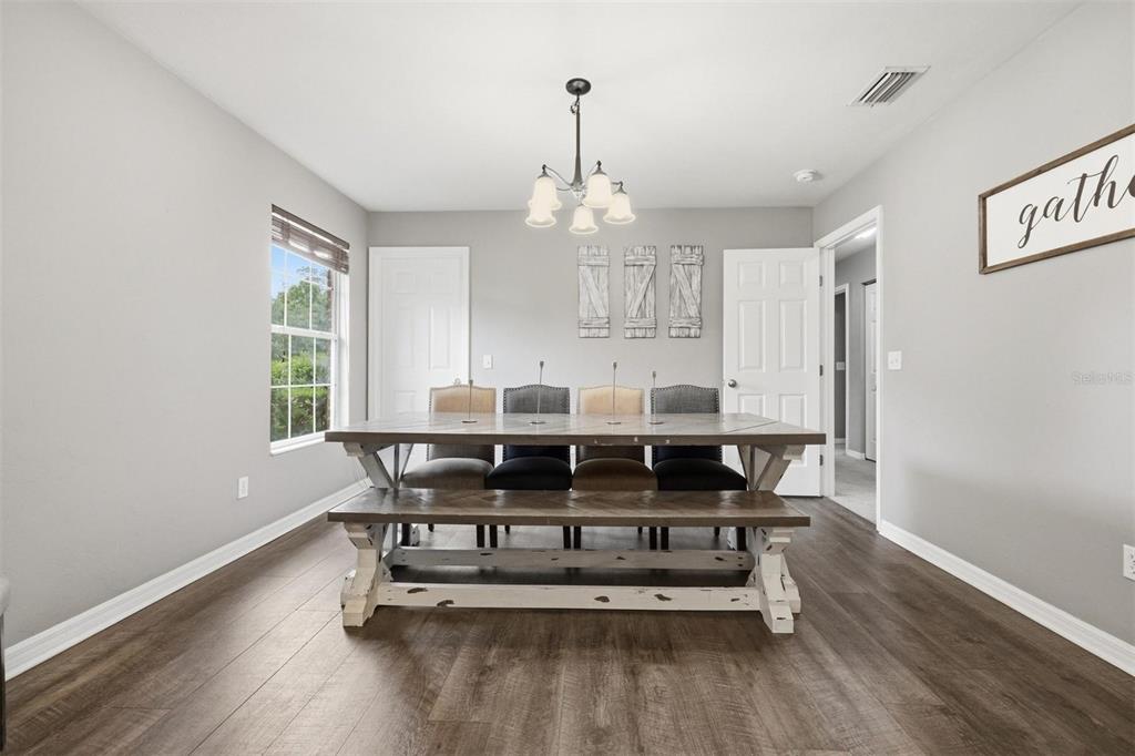 A dining room features a wooden table with a bench, four chairs, and light-colored walls — 3460 SE COUNTY ROAD 337, TRENTON, FL