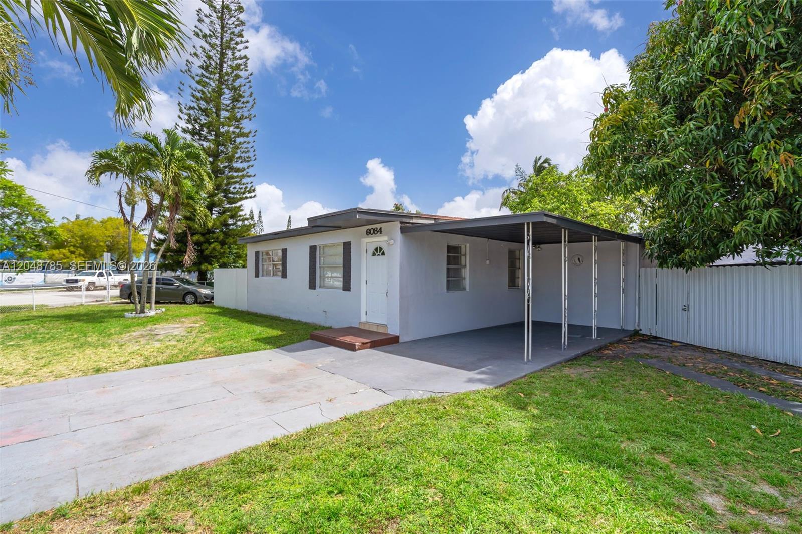 A single-story house with a carport and a concrete driveway sits on a grassy lot — 6084 E 7th Ave, Hialeah FL 33013, HIALEAH, FL