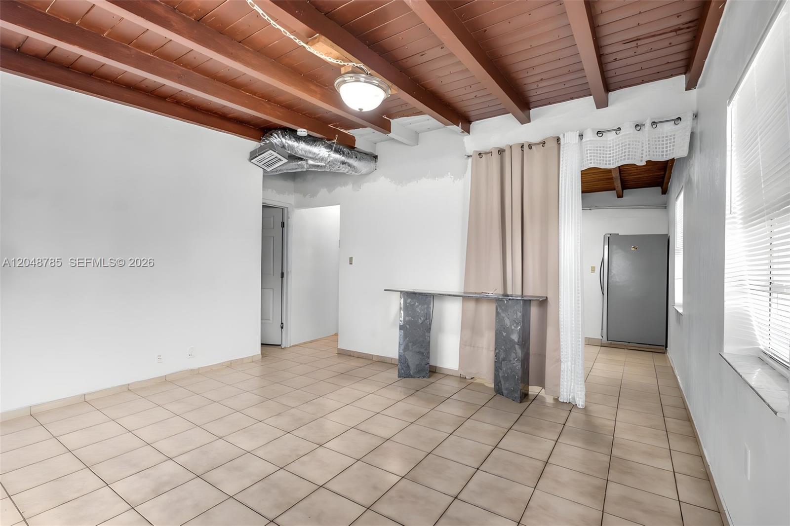 A room with tiled floors, exposed wood ceiling beams, and a marble-topped console table — 6084 E 7th Ave, Hialeah FL 33013, HIALEAH, FL