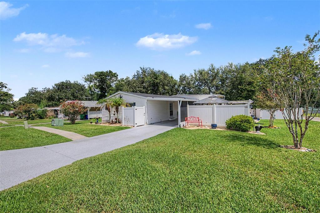 A single-story mobile home with a white exterior, driveway, and white vinyl privacy fencing — 37719 NEWAL AVENUE, ZEPHYRHILLS, FL