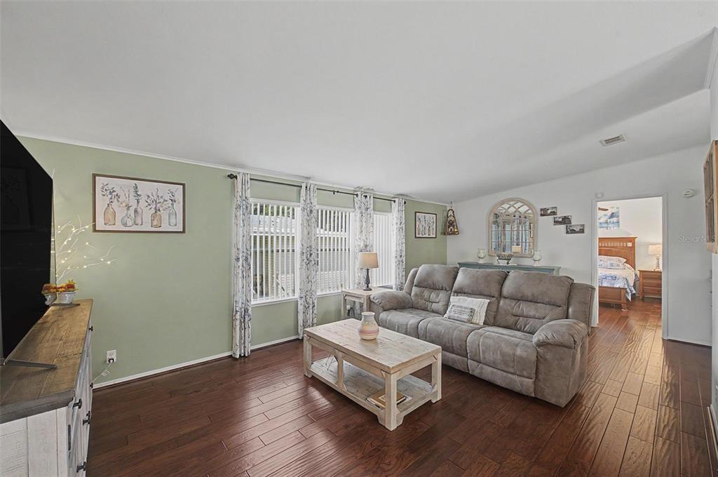 A living room features sage green walls, dark wood flooring, and a gray reclining sofa — 37719 NEWAL AVENUE, ZEPHYRHILLS, FL