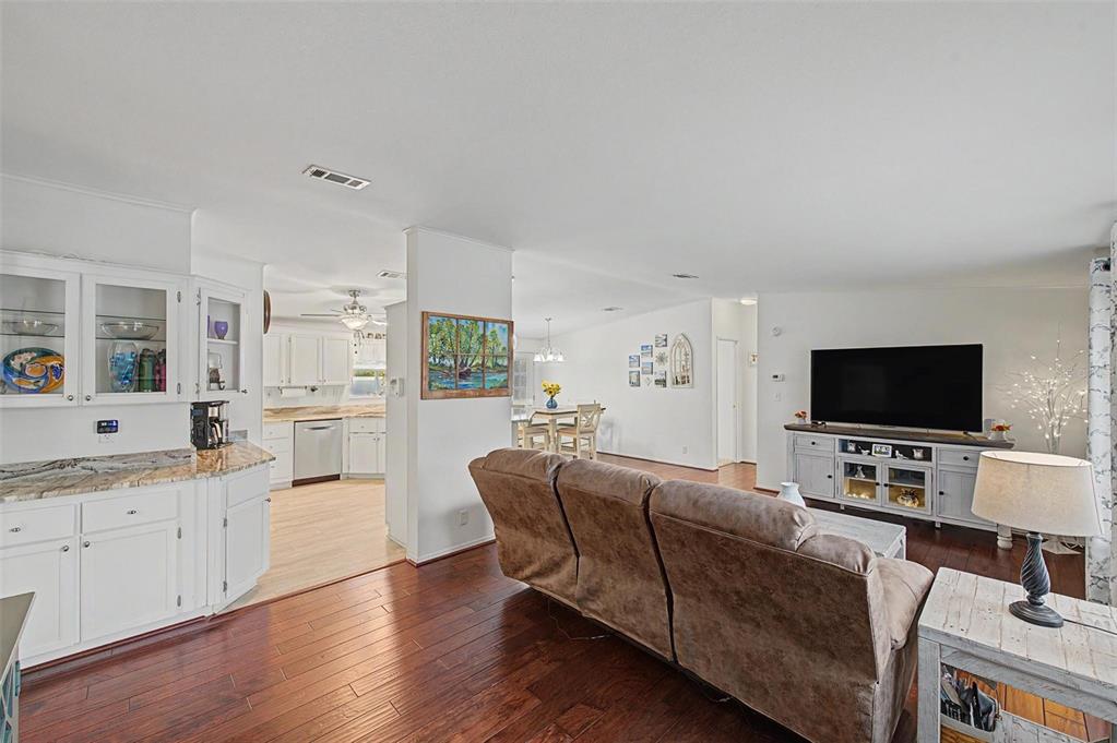 A living room with hardwood floors, a brown sofa, and an open view into the kitchen — 37719 NEWAL AVENUE, ZEPHYRHILLS, FL
