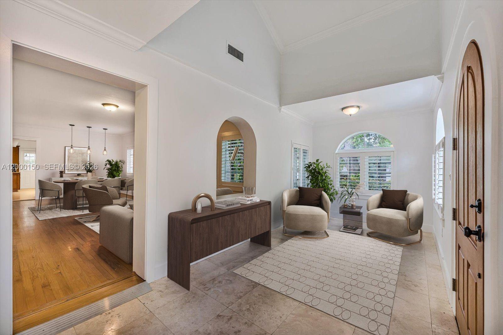 A bright entryway features a vaulted ceiling, tiled floors, two armchairs, and a wooden console — 1102 Genoa St, Coral Gables FL 33134, CORAL GABLES, FL
