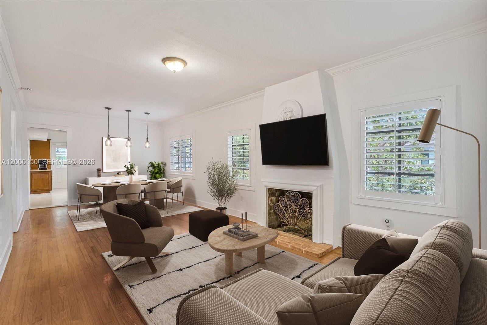 A living room features a fireplace with a mounted television, hardwood floors, and dining area — 1102 Genoa St, Coral Gables FL 33134, CORAL GABLES, FL