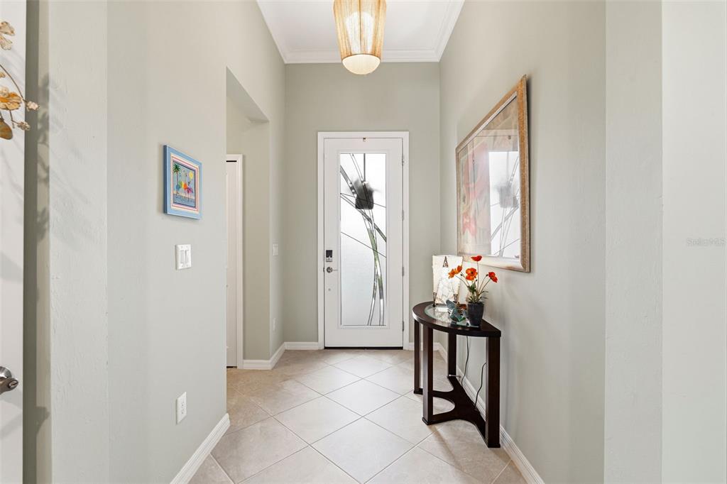 A bright entryway features light-colored walls, tile flooring, a glass-paneled front door, and a console table — 1793 SADDLEWOOD CIRCLE, PORT CHARLOTTE, FL