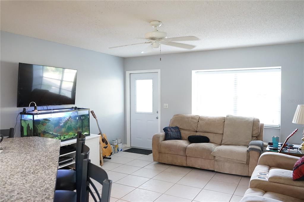 A living room features light gray walls, tile flooring, a ceiling fan, and a fish tank — 424 LAKE POINT COURT UNIT 5A, SUN CITY CENTER, FL