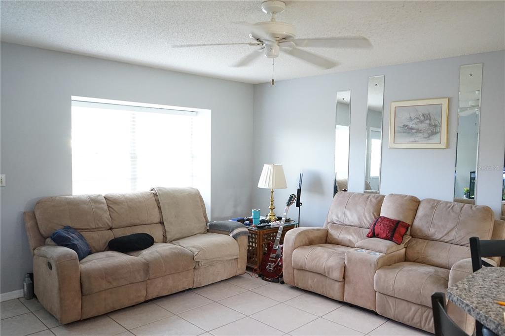 A living room features two tan reclining sofas, a ceiling fan, and tiled flooring — 424 LAKE POINT COURT UNIT 5A, SUN CITY CENTER, FL