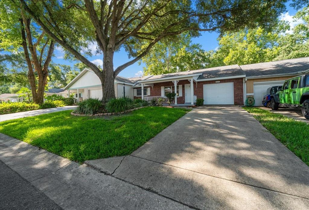 A single-story brick house with a concrete driveway and a large tree in the yard — 8874 SW 95TH STREET UNIT C, OCALA, FL
