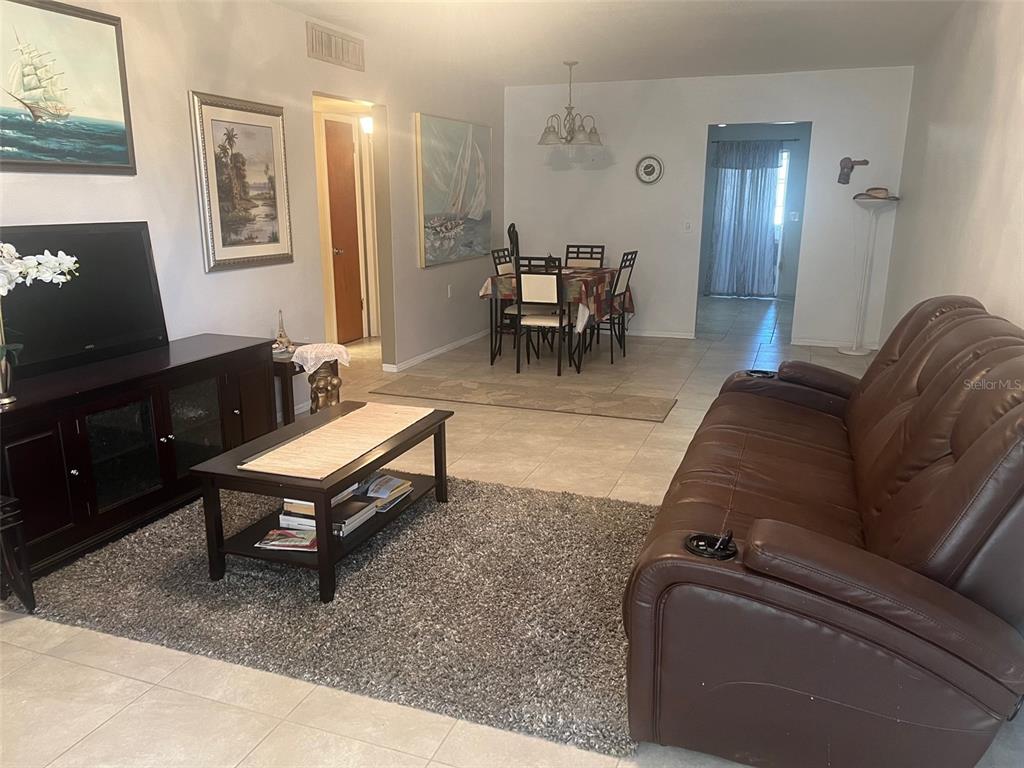 A living room and dining area with tile flooring, a brown leather sofa, and artwork — 5155 9TH AVENUE N UNIT 302, ST PETERSBURG, FL