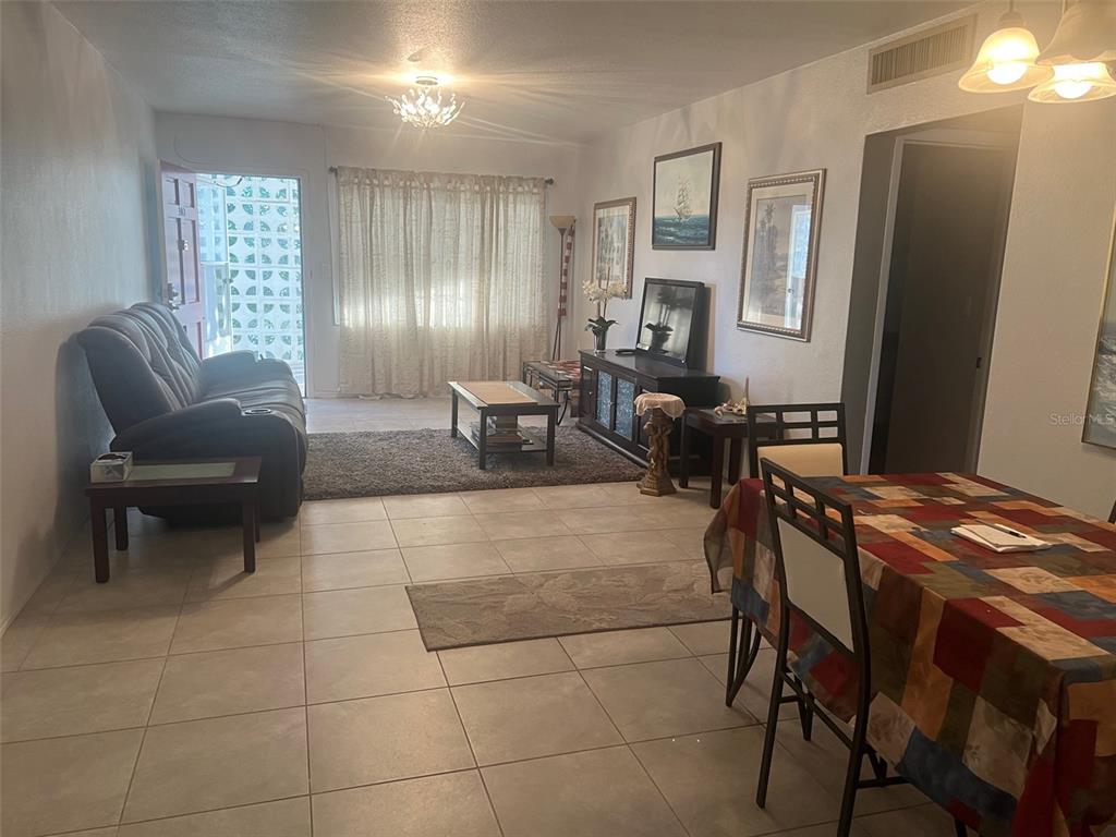 A living room and dining area feature tile flooring, a dark sofa, and a table — 5155 9TH AVENUE N UNIT 302, ST PETERSBURG, FL