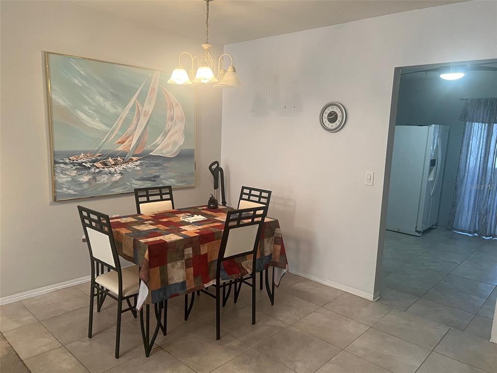 A dining area features a table with four chairs, a sailboat painting, and tile flooring — 5155 9TH AVENUE N UNIT 302, ST PETERSBURG, FL