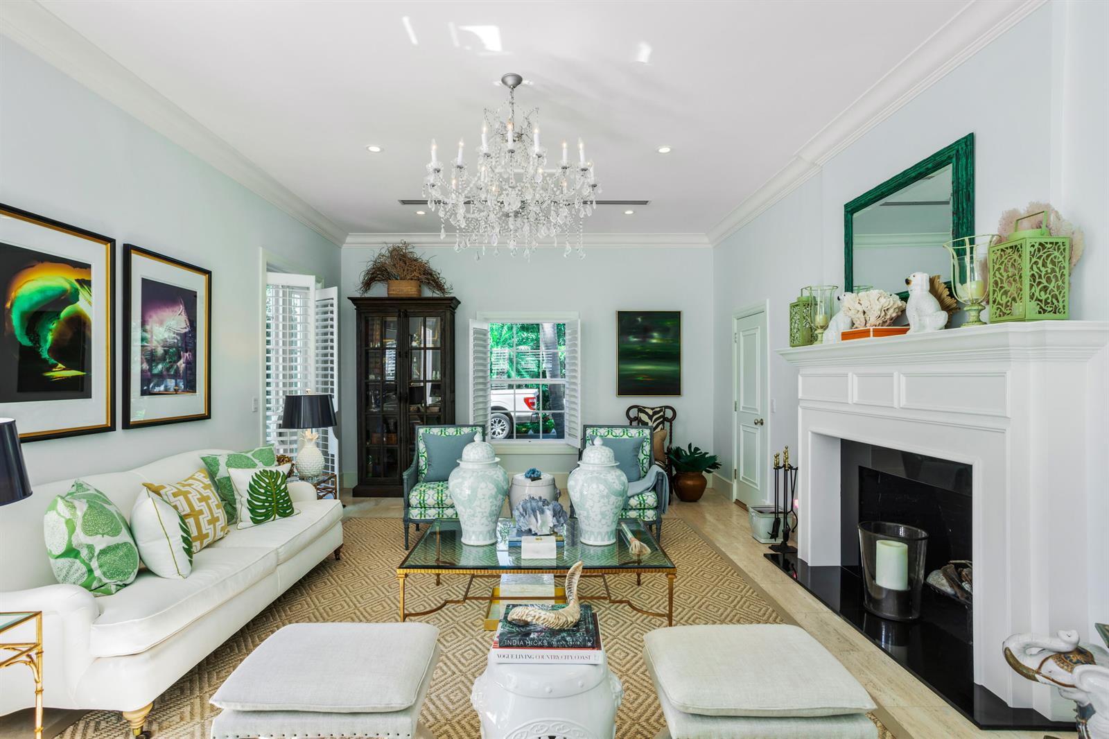 A bright living room features a white fireplace, crystal chandelier, and green accent decor — 327 Arabian Road, Palm Beach FL 33480, PALM BEACH, FL