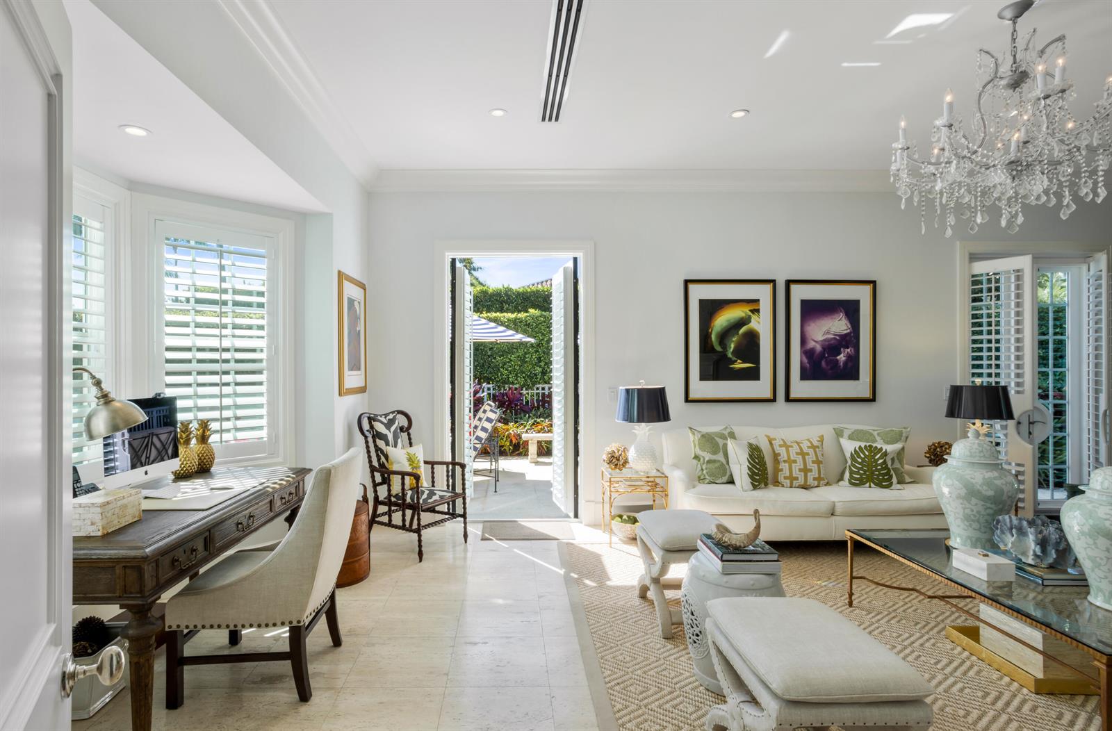 A bright living room features a desk, sofa, chandelier, and glass doors opening to a patio — 327 Arabian Road, Palm Beach FL 33480, PALM BEACH, FL