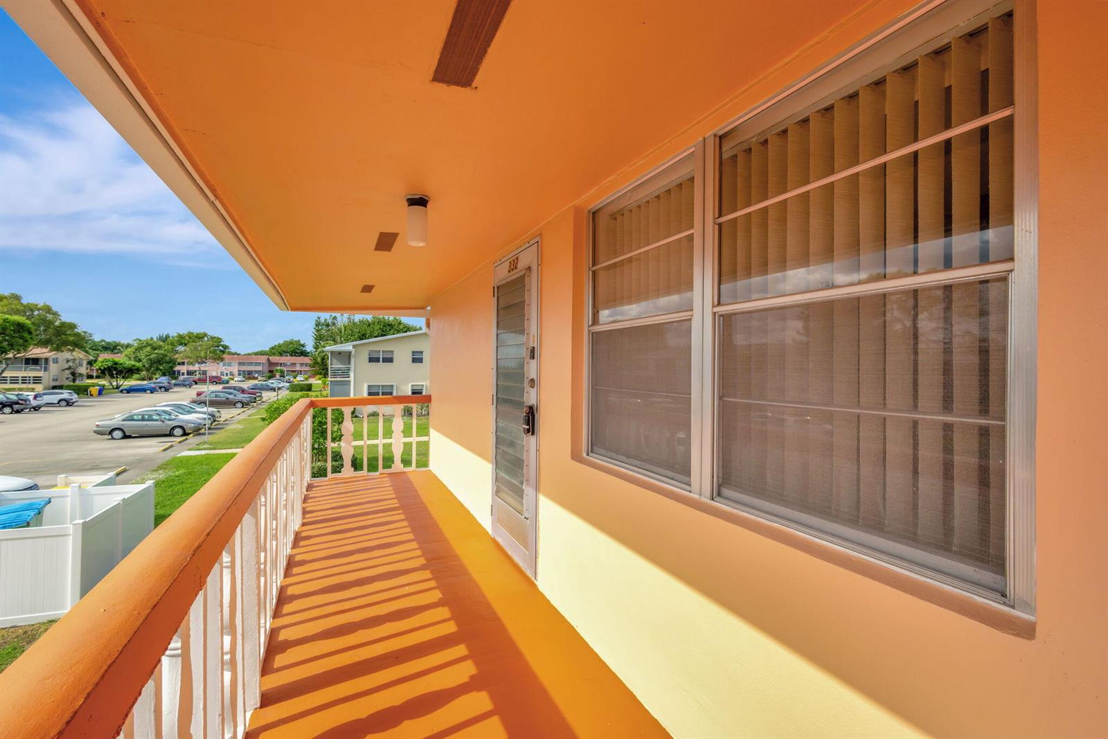 An orange exterior balcony features a white railing, a screen door, and large windows — 332 Sheffield N, West Palm Beach FL 33417, WEST PALM BEACH, FL